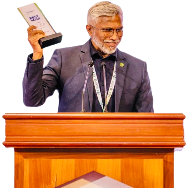 Mohamed Shareef at a lectern, smiling and holding up the Best Paper award he received at ICIA 2026